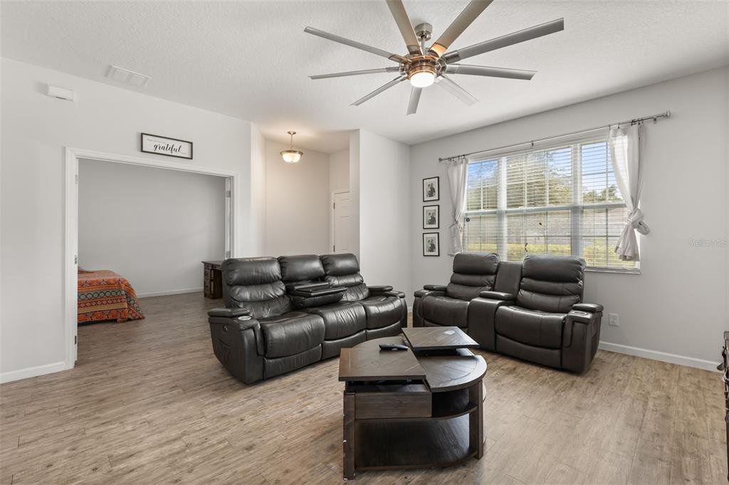 A living room features dark leather reclining sofas, a wooden coffee table, and wood-look flooring — 2427 LINER AVENUE, APOPKA, FL