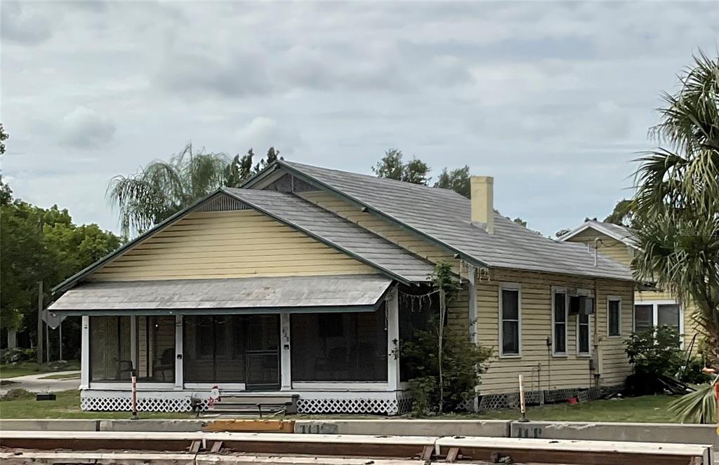 A yellow, single-story house with a screened-in front porch and a metal roof — 628 E MAGNOLIA STREET, ARCADIA, FL