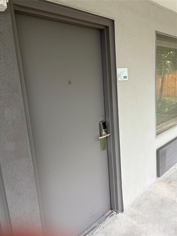 A gray exterior door with a digital lock and unit number 503 is shown — 7150 N TAMIAMI TRL UNIT S503, SARASOTA, FL