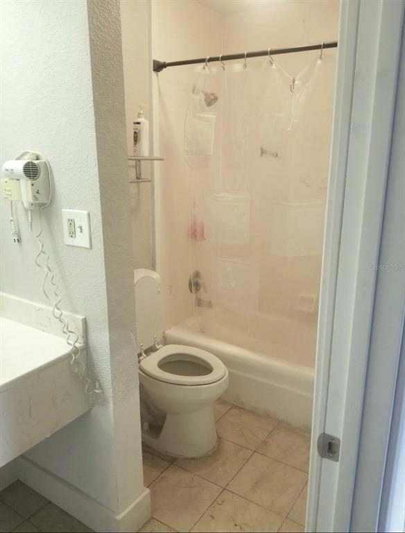 A bathroom features a toilet, a bathtub with a shower, and a wall-mounted hair dryer — 7150 N TAMIAMI TRL UNIT S503, SARASOTA, FL
