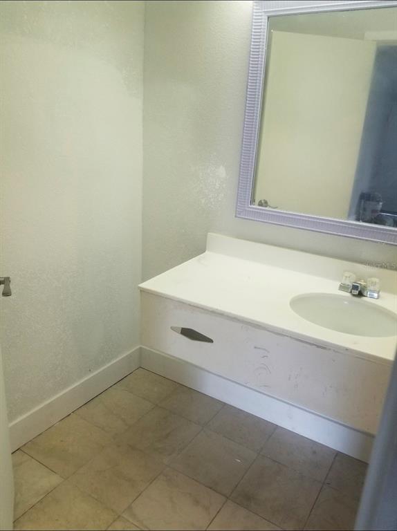 A bathroom features a white vanity with a sink, a mirror, and tiled flooring — 7150 N TAMIAMI TRL UNIT S503, SARASOTA, FL
