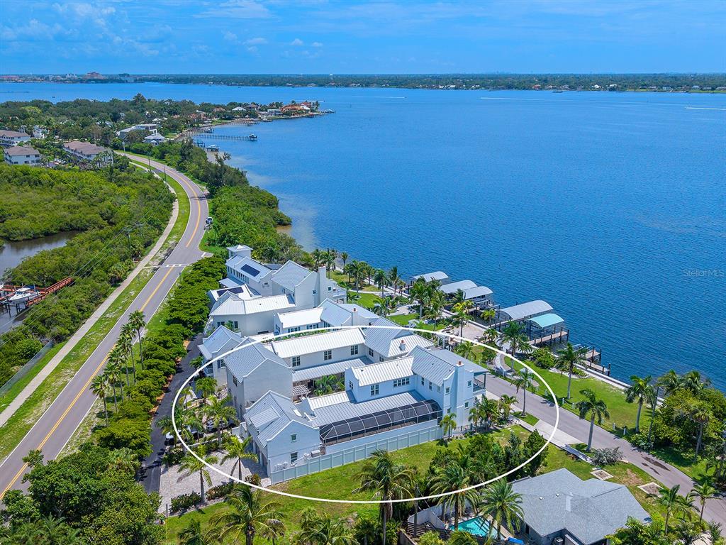 An aerial view of a large white waterfront house with a pool enclosure and docks — 4024 11TH STREET COURT W, PALMETTO, FL