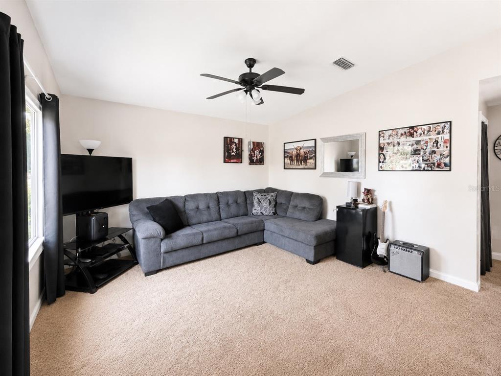 A living room features a grey sectional sofa, a television on a stand, and beige carpeting — 35 ALMOND ROAD, OCALA, FL