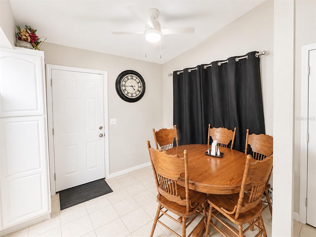 A dining area features a round wooden table, four chairs, a wall clock, and curtains — 35 ALMOND ROAD, OCALA, FL