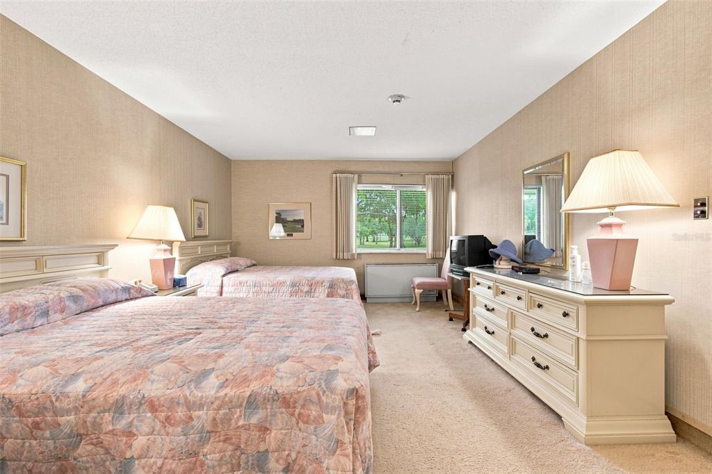 A bedroom features two beds with floral bedding, beige wallpaper, and a white dresser — 36750 US HIGHWAY 19 UNIT 21105, PALM HARBOR, FL