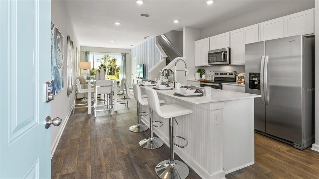 A modern kitchen features white cabinetry, stainless steel appliances, and a breakfast bar with stools — 36 SAGE BRANCH STREET, ST AUGUSTINE, FL