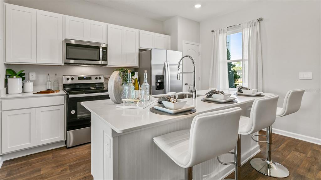 A modern kitchen features white cabinets, stainless steel appliances, and a central island with seating — 36 SAGE BRANCH STREET, ST AUGUSTINE, FL