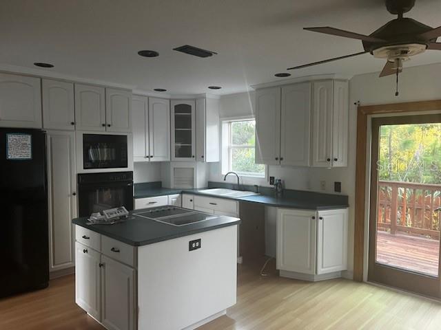 A kitchen with white cabinets, a dark island, and a door leading to a deck — 33 SEVEN WONDERS TRAIL, PALM COAST, FL