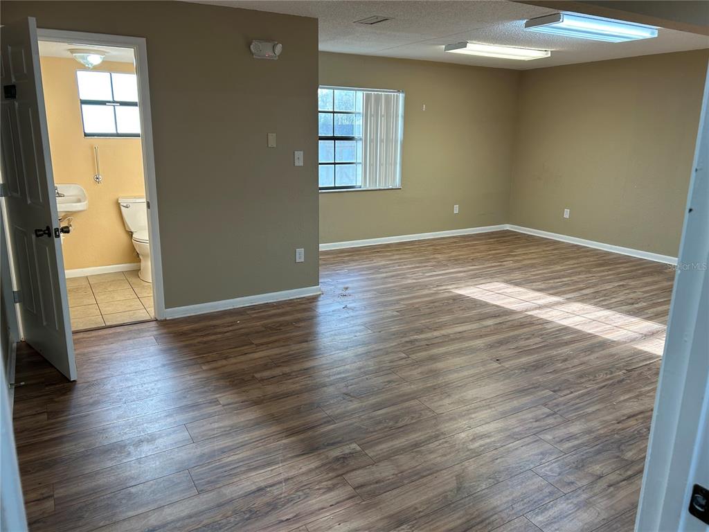 An empty room with wood-look flooring, beige walls, and an attached bathroom — 2945 NE 3RD STREET UNIT 203, OCALA, FL