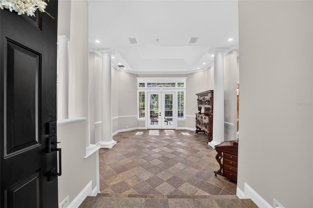 A foyer with tile flooring, white columns, and a double-door entrance with glass panels — 7050 SE 12TH CIRCLE, OCALA, FL