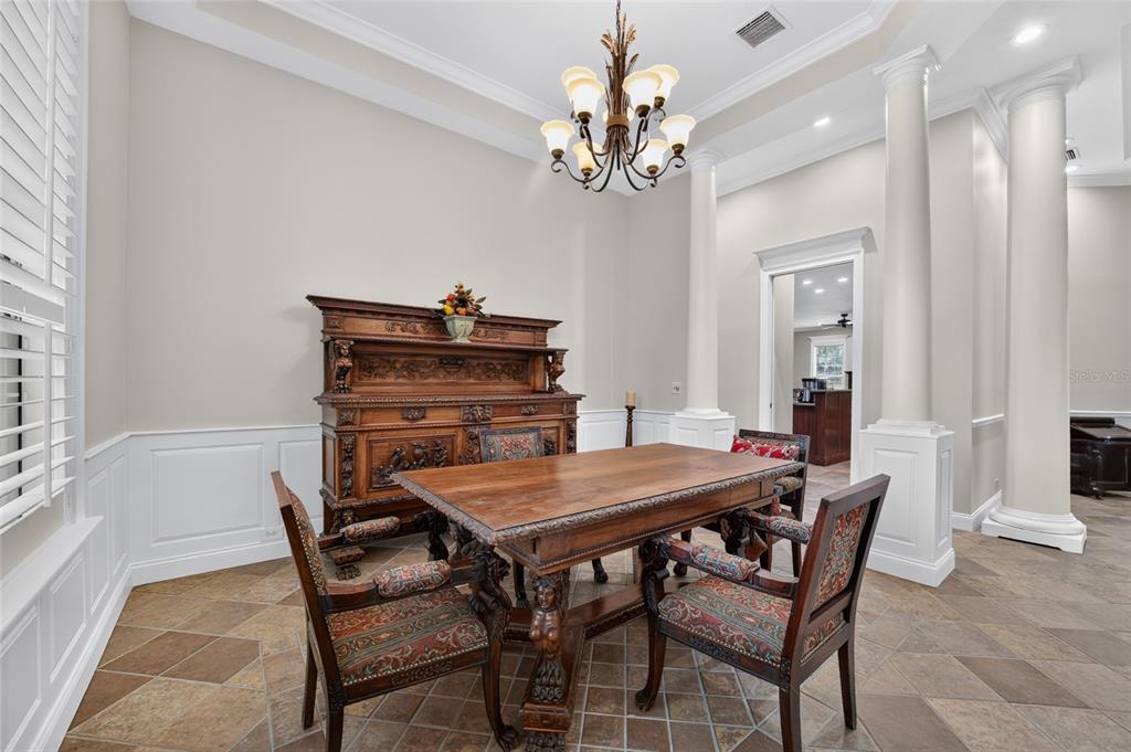 A dining room features a wooden table, ornate chairs, a large hutch, and white columns — 7050 SE 12TH CIRCLE, OCALA, FL