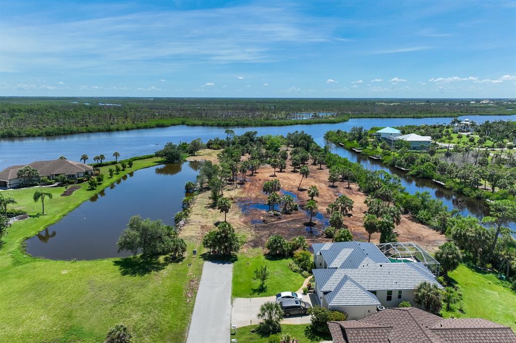 An aerial view shows a cleared waterfront lot surrounded by houses, palm trees, and canals — 4700 ARLINGTON DRIVE, PLACIDA, FL
