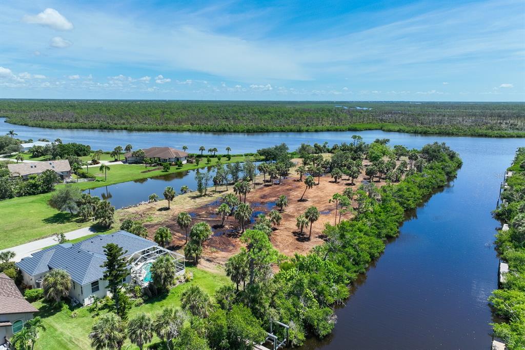 An aerial view shows a cleared waterfront lot surrounded by trees, canals, and residential homes — 4700 ARLINGTON DRIVE, PLACIDA, FL