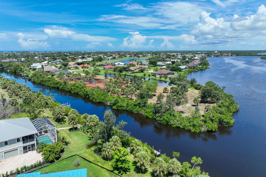 An aerial view shows a waterfront house with a pool near a river and neighborhood — 4700 ARLINGTON DRIVE, PLACIDA, FL
