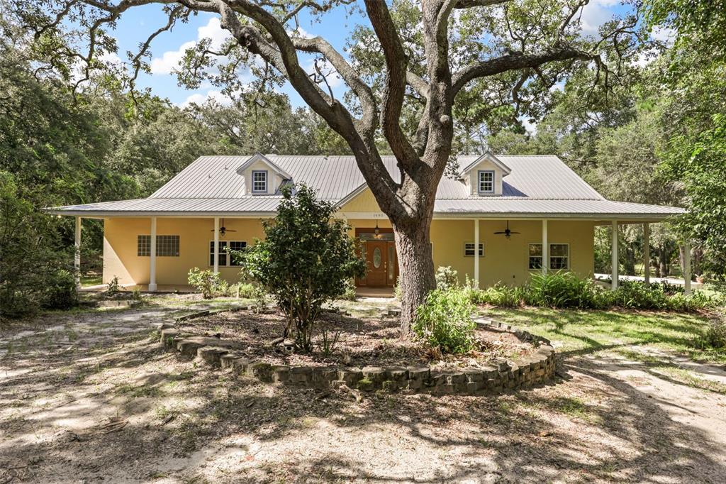 A yellow house with a metal roof and a large oak tree in the front yard — 1685 MANOR WAY, DELAND, FL