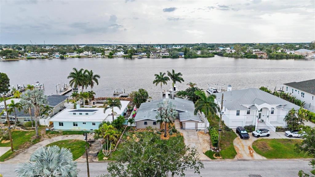 An aerial view of three waterfront houses with palm trees and docks along a river — 704 BAYSHORE DRIVE, TARPON SPRINGS, FL