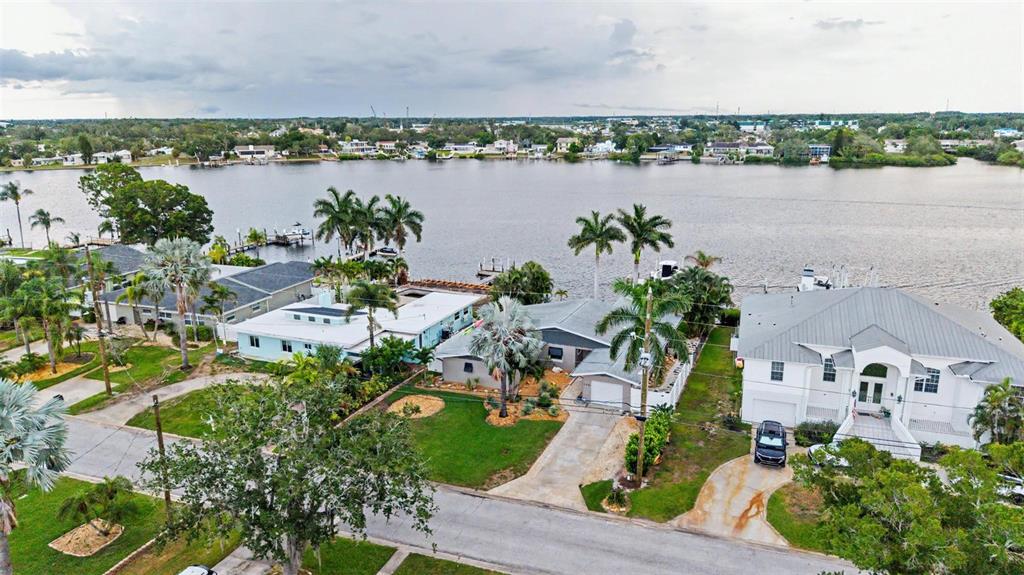 An aerial view shows waterfront houses with palm trees, driveways, and docks along a canal — 704 BAYSHORE DRIVE, TARPON SPRINGS, FL