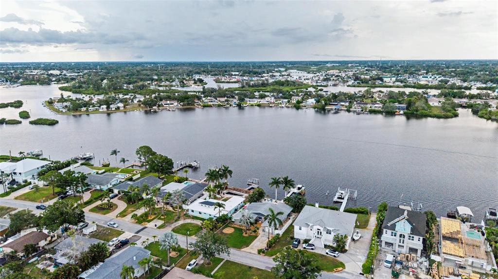 An aerial view shows waterfront houses with docks along a canal under a cloudy sky — 704 BAYSHORE DRIVE, TARPON SPRINGS, FL