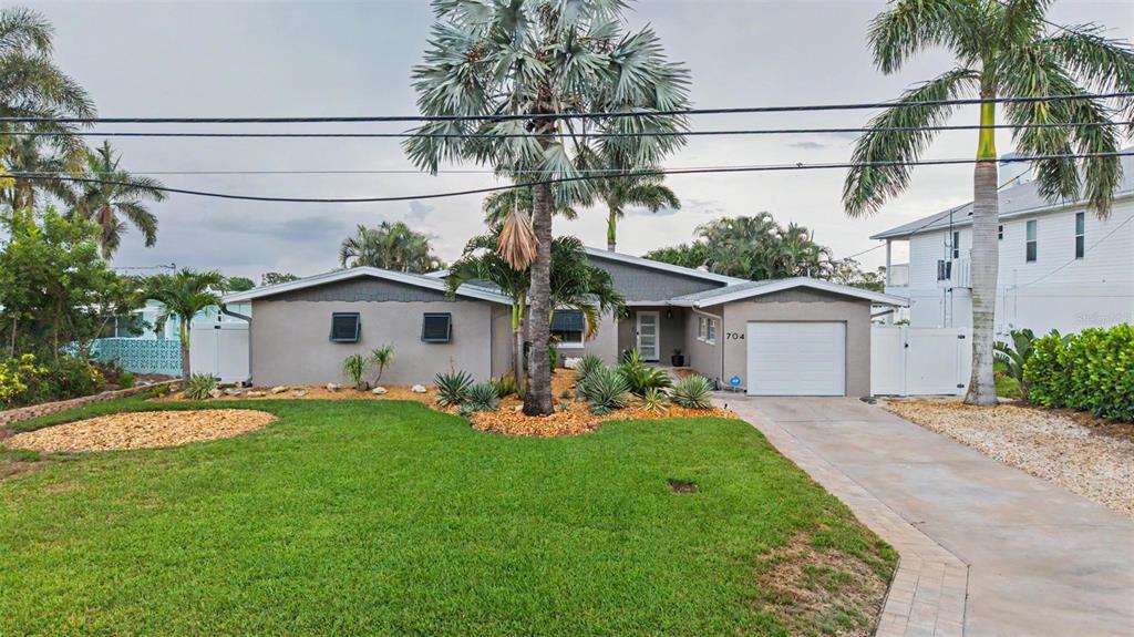 A single-story house with a gray exterior, a garage, and palm trees in the front yard — 704 BAYSHORE DRIVE, TARPON SPRINGS, FL