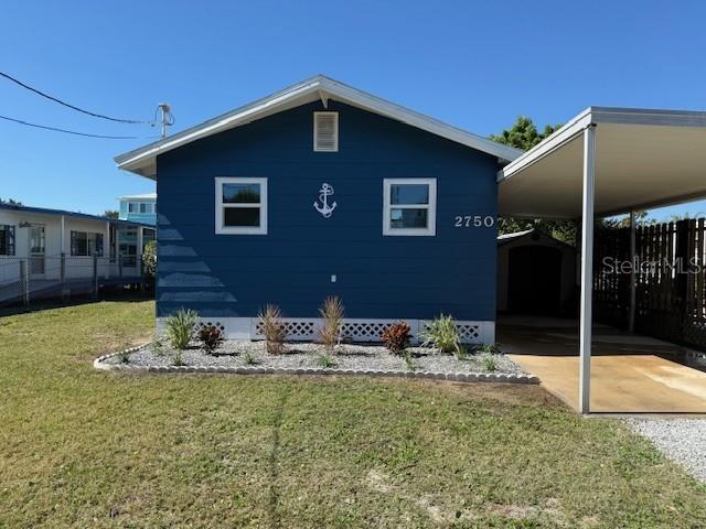 A blue house with a white anchor decoration and an attached carport sits on grass — 2750 N COMANCHE POINT, CRYSTAL RIVER, FL