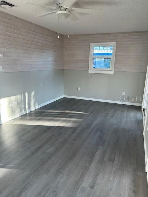 An empty room features wood-paneled walls, gray flooring, and a ceiling fan — 2750 N COMANCHE POINT, CRYSTAL RIVER, FL