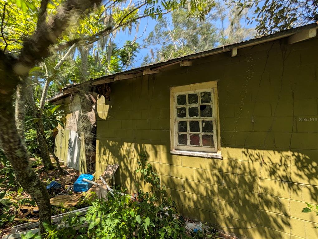An exterior view of a weathered, olive-green concrete block building with a multi-pane window — 700 GRANT AVENUE, DELAND, FL