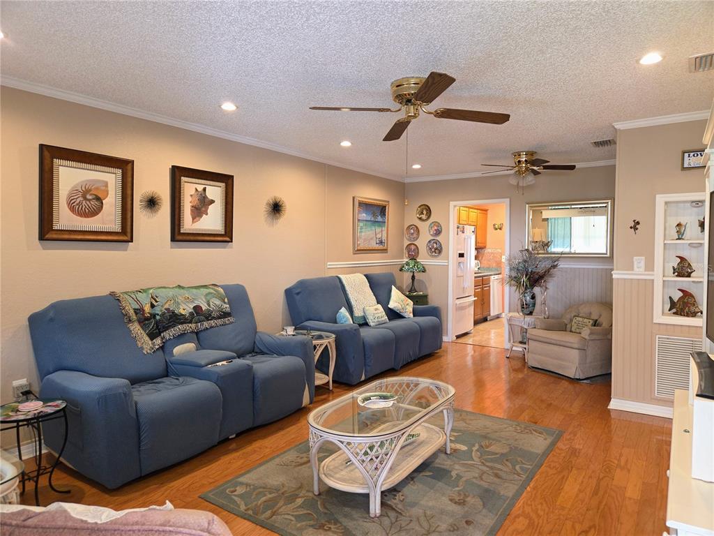 A living room features blue sofas, a glass-topped coffee table, and hardwood flooring — 10036 63RD AVENUE N UNIT 23, ST PETERSBURG, FL