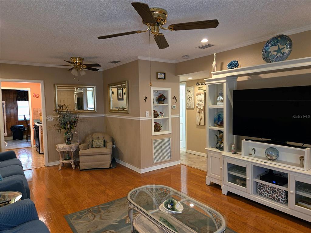 A living room features hardwood floors, a ceiling fan, a television console, and beige walls — 10036 63RD AVENUE N UNIT 23, ST PETERSBURG, FL
