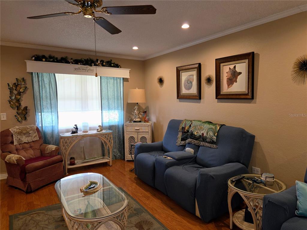 A living room features a blue sofa, a recliner, a glass coffee table, and wall art — 10036 63RD AVENUE N UNIT 23, ST PETERSBURG, FL