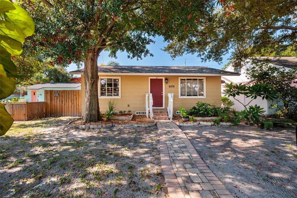 A tan single-story house with a red front door and a paved walkway — 6376 4TH AVENUE S, ST PETERSBURG, FL
