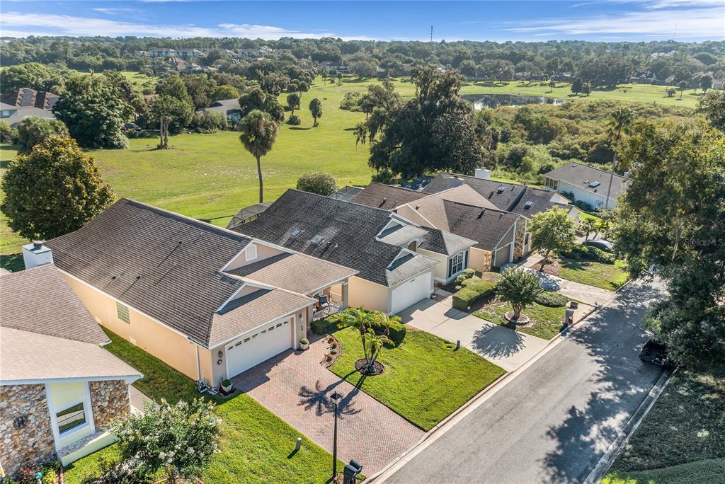 An aerial view shows a suburban house with a brick driveway and a large backyard — 1036 LINKSIDE COURT, APOPKA, FL