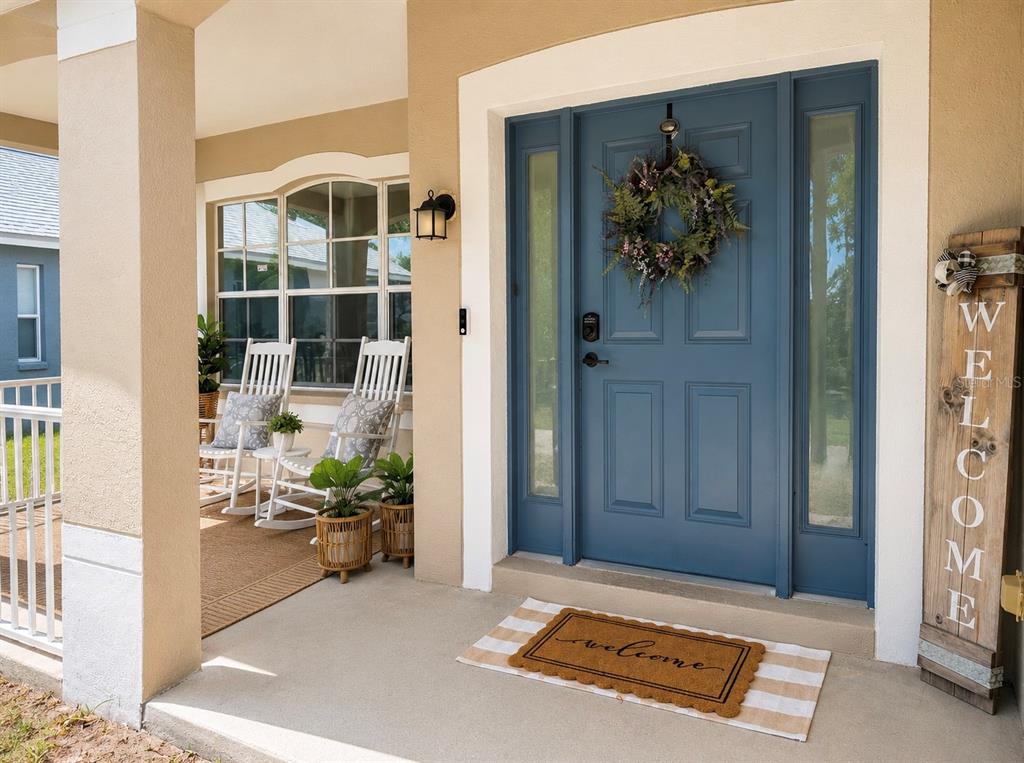 A blue front door with a wreath sits on a porch with two white rocking chairs — 6801 CAMBRIDGE PARK DRIVE, APOLLO BEACH, FL