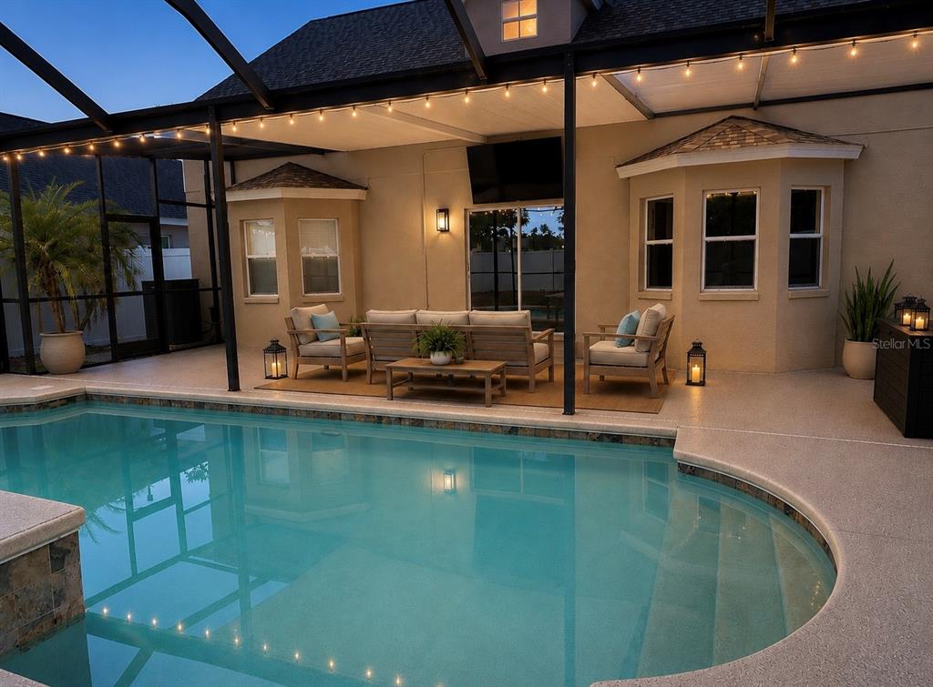 A covered patio with outdoor furniture overlooks a swimming pool enclosed by a screen — 6801 CAMBRIDGE PARK DRIVE, APOLLO BEACH, FL