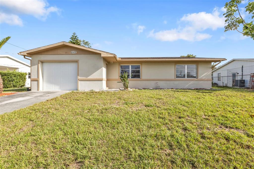 A single-story house with a beige stucco exterior, a one-car garage, and a grassy lawn — 8172 TRIONFO AVENUE, NORTH PORT, FL
