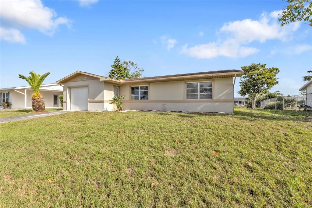 A single-story house with a beige exterior, a one-car garage, and a front lawn — 8172 TRIONFO AVENUE, NORTH PORT, FL