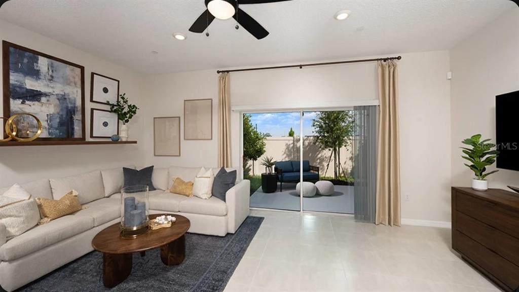 A living room features a sectional sofa, a coffee table, and sliding doors to a patio — 2517 BALMERINO WAY UNIT 0, MOUNT DORA, FL
