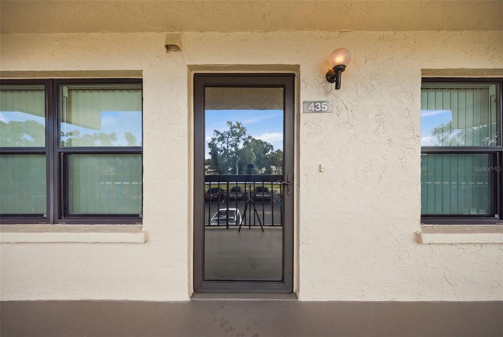 The exterior view shows a building entrance with a glass storm door and two windows — 435 30TH AVENUE W UNIT D206, BRADENTON, FL