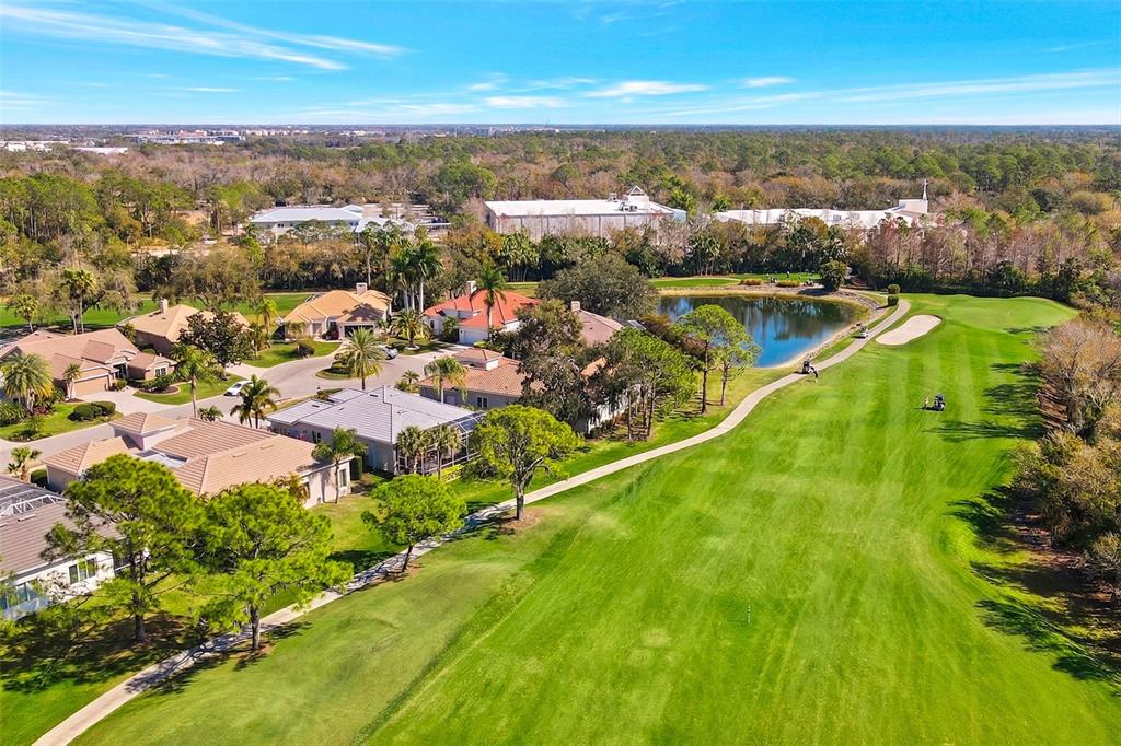 An aerial view shows residential houses bordering a golf course fairway and a small pond — 8732 54TH AVENUE E, BRADENTON, FL
