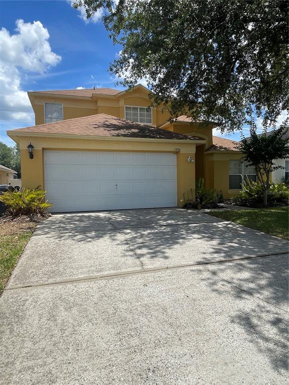 A two-story yellow house features a two-car garage and a concrete driveway — 1336 CASTERTON CIRCLE, DAVENPORT, FL