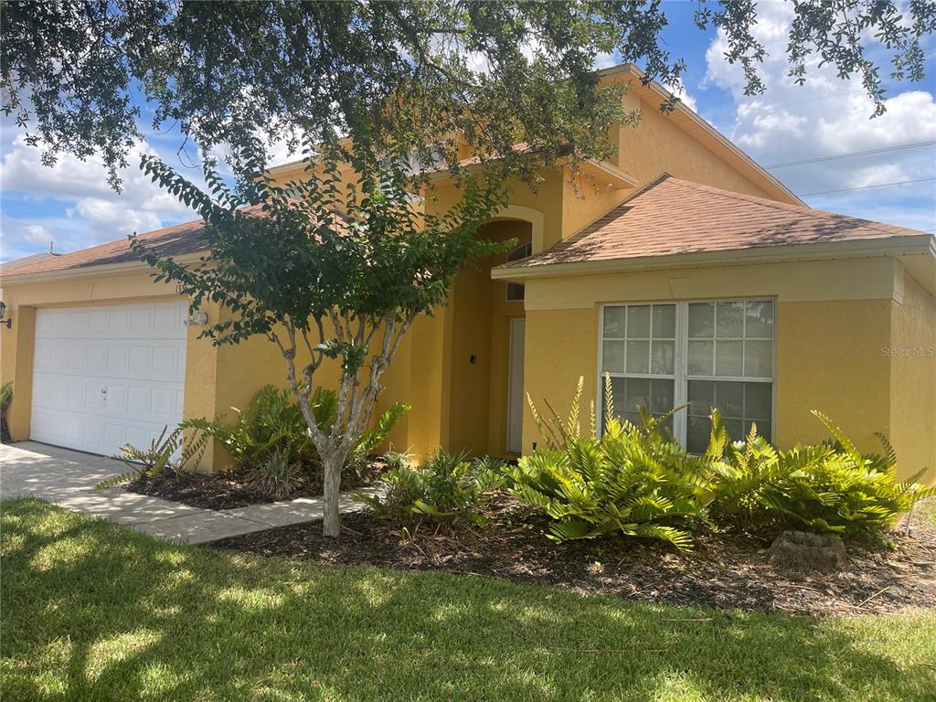 A yellow stucco house with a two-car garage and a front garden — 1336 CASTERTON CIRCLE, DAVENPORT, FL