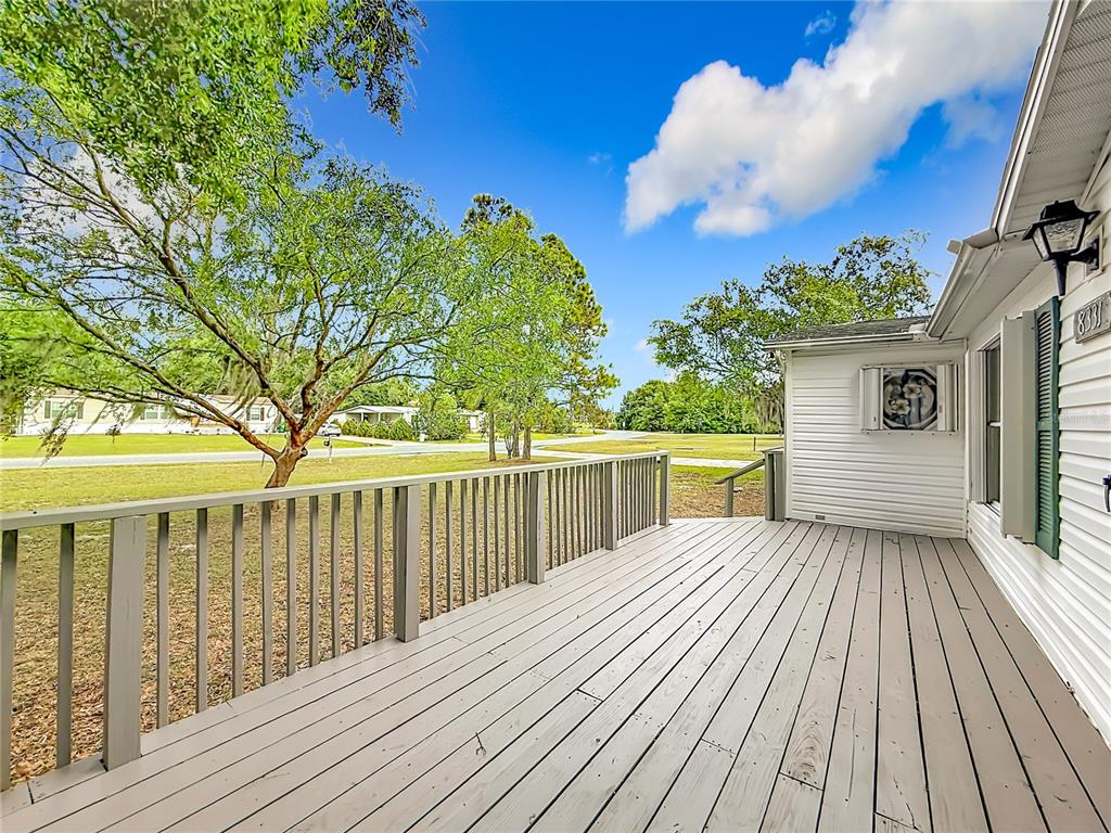 A kitchen with white cabinets, tile countertops, stainless steel appliances, and light wood-look flooring — 8331 COUNTY ROAD 109, LADY LAKE, FL