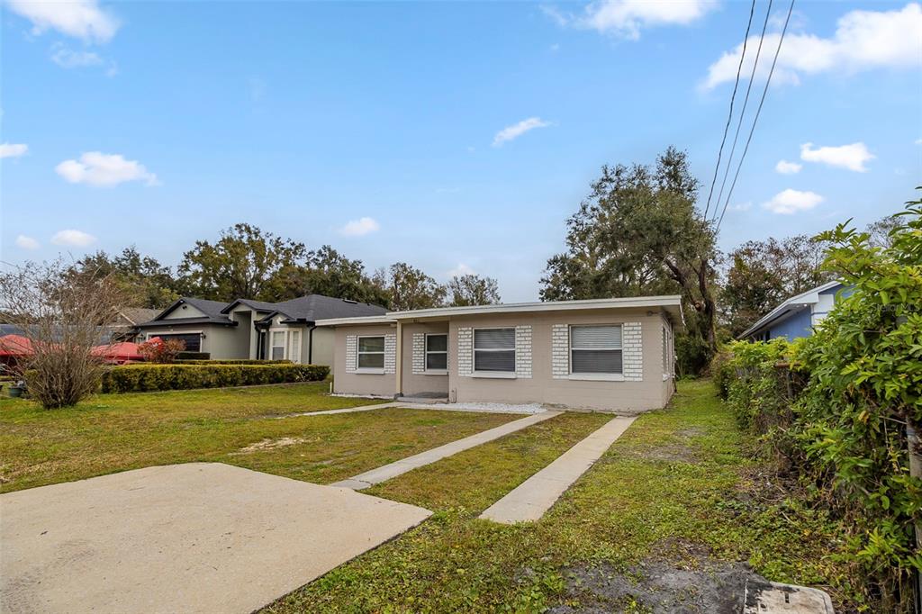 A single-story house with a beige exterior, a flat roof, and a concrete driveway — 451 ROGERS STREET, ORLANDO, FL