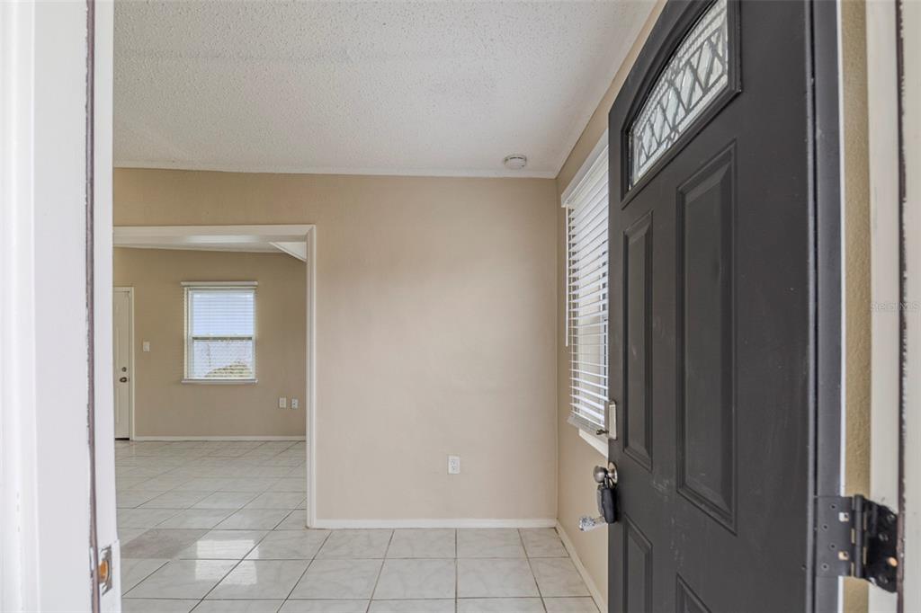 An entryway with white tile floors leads into a living area with a window — 451 ROGERS STREET, ORLANDO, FL