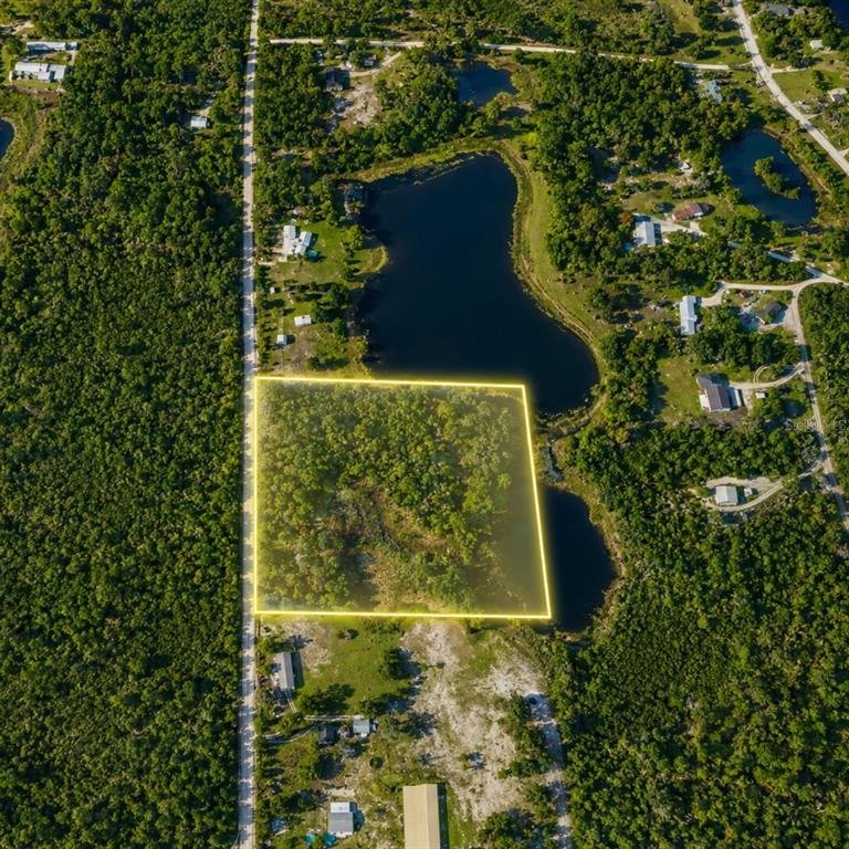 An aerial view shows a rectangular plot of land highlighted in yellow near a lake — LESLIE DRIVE, DELAND, FL