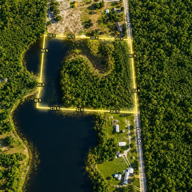 An aerial view shows a property boundary outlined in yellow over a lake and woods — LESLIE DRIVE, DELAND, FL