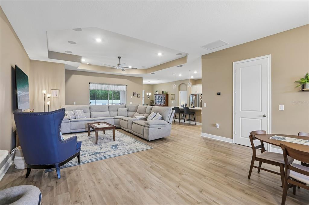 An open-concept living room features a tray ceiling, light wood flooring, and a sectional sofa — 902 TIERRA DR, SPRING HILL, FL