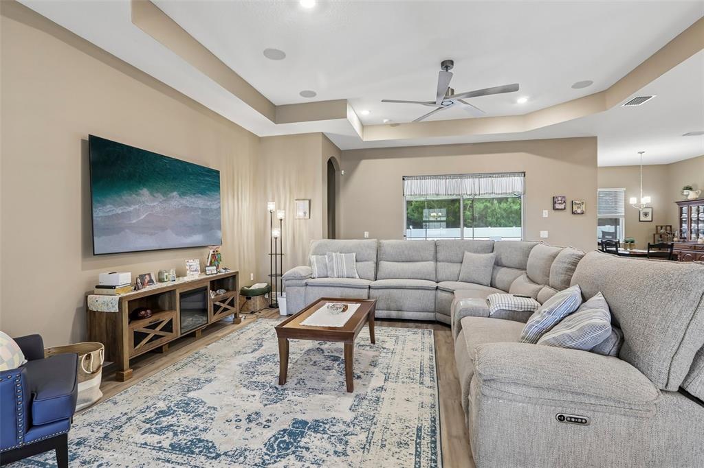 A living room features a large sectional sofa, a television, and a patterned area rug — 902 TIERRA DR, SPRING HILL, FL