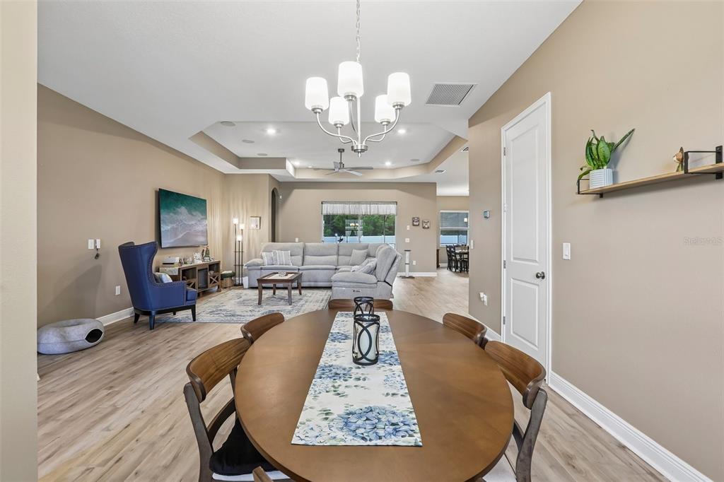 A dining area with a round wooden table opens into a living room with a sectional — 902 TIERRA DR, SPRING HILL, FL