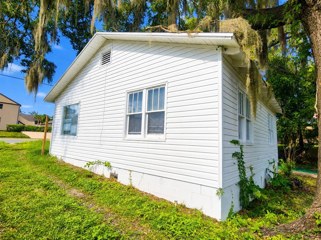 The exterior of a white, single-story house with horizontal siding and a concrete block foundation — 617 NE 25TH AVENUE, OCALA, FL