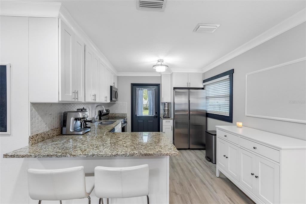 A kitchen features white cabinets, granite countertops, stainless steel appliances, and a breakfast bar — 6114 N 23RD STREET, TAMPA, FL